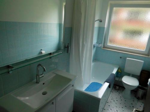 a bathroom with a sink and a toilet and a window at Maggie's Goode Stuuv in Heiligenhafen