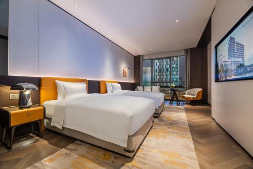 a hotel room with two beds and a television at Novotel Xian Xixian in Xi'an