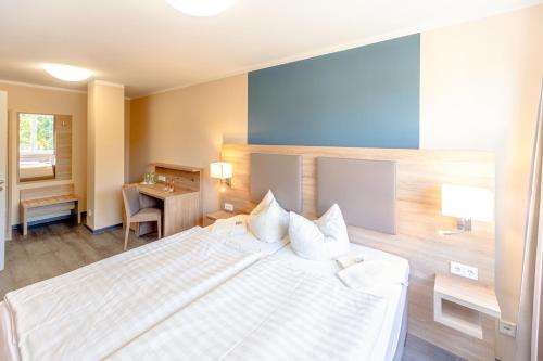 a bedroom with a large white bed and a desk at Hotel Rügenblick in Stralsund