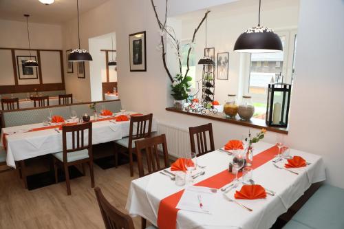 a restaurant with white tables and chairs with orange napkins at Alpenhotel Ensmann in Göstling an der Ybbs