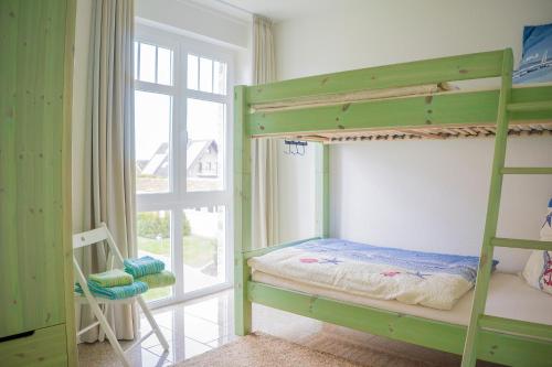Neue Tiefe FehmarnにあるSchmuckstück am Binnenseeの窓付きのお部屋の緑色の二段ベッド1台分です。