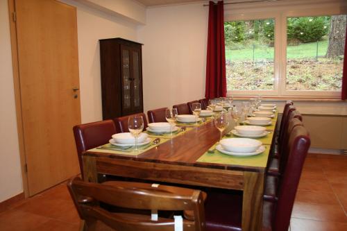 a long wooden table with chairs and wine glasses at Ferienhaus Maria Magdalena in Bad Lauterberg
