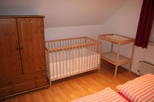 a bedroom with a crib and a wooden cabinet at Ferienhaus Maria Magdalena in Bad Lauterberg