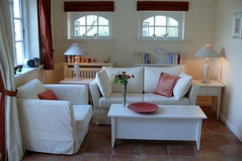 ein Wohnzimmer mit einem weißen Sofa und einem Tisch in der Unterkunft Deichhof Whg18 in Dunsum