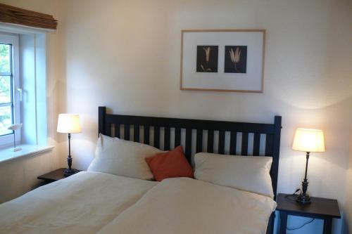 a bedroom with a white bed with two lamps at Deichhof Whg18 in Dunsum