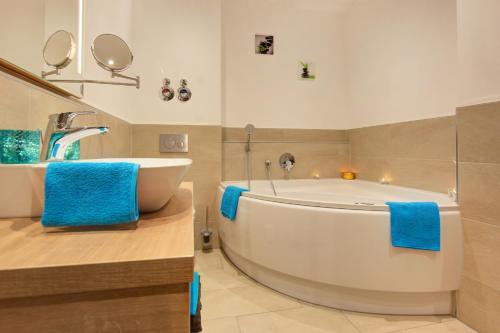 a bathroom with a tub and a sink with blue towels at Forest 306 in Feldberg