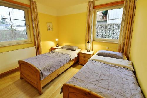 two beds in a room with two windows at Haus Marleen EG, FW 1 in Zingst