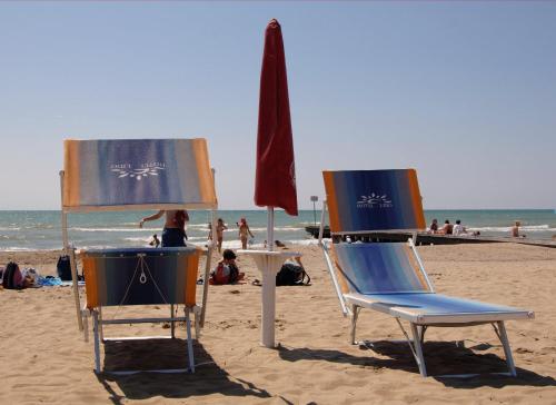 two chairs and an umbrella on a beach at Hotel Lido in Lido di Jesolo