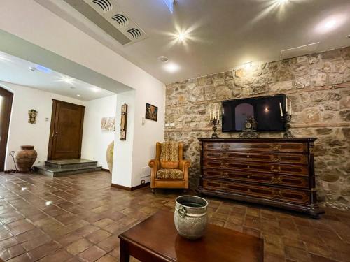 a living room with a tv on a stone wall at Hotel La Plumeria in Cefalù