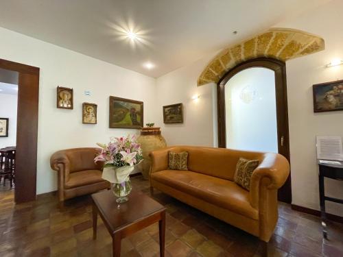 a living room with a couch and a table with flowers at Hotel La Plumeria in Cefalù