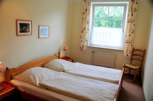 a bedroom with a bed and a window and a chair at Ferienwohnung 4, EG, Hof zur Sonnenseite Fehmarn in Fehmarn