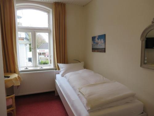 Bett in einem Zimmer mit Fenster in der Unterkunft Pension Hilligenlei Zi 01 EZ in Wyk auf Föhr