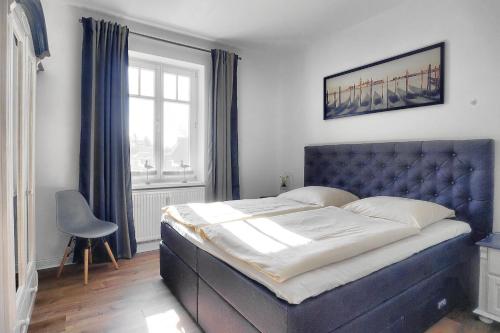 a bedroom with a bed with a blue headboard and a window at Villa Balticum, Whg 4 in Zingst