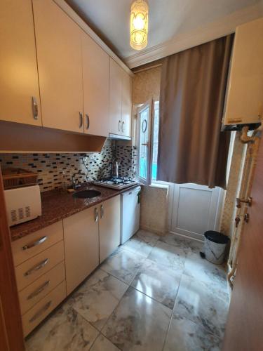 a small kitchen with white cabinets and a window at Efe Apart Hotel in Istanbul