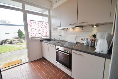 a kitchen with white cabinets and a sink and a window at An der Allee 20 C in Dahme