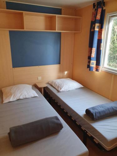 deux lits dans une petite pièce avec une fenêtre dans l'établissement Mobile-home, à Saint-Chéron