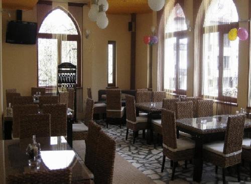 un comedor con mesas, sillas y ventanas en The Castle Hotel en Samokov