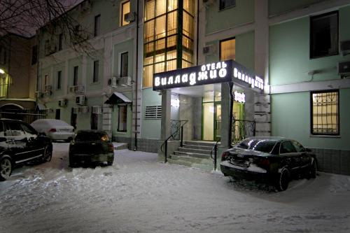 モスクワにあるВилладжио Отельの雪中の建物の外に停車した車2台