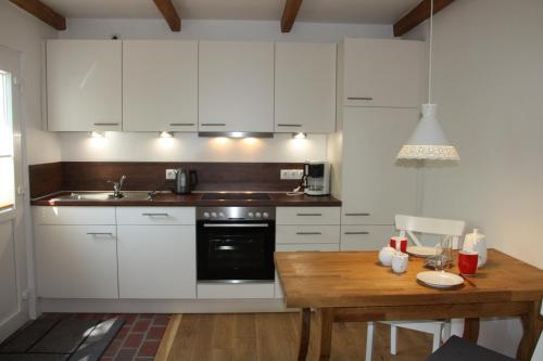 cocina con armarios blancos y mesa de madera en Feldlerche, en Neue Tiefe Fehmarn