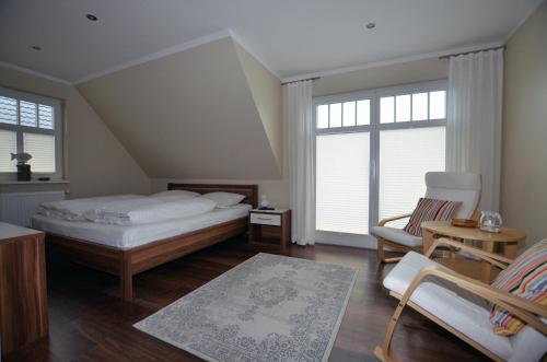 a bedroom with a bed and a chair and windows at Haus Lobster in Zingst