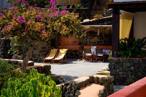 a patio with chairs and a tree with purple flowers at Venus Dream in Pantelleria