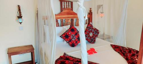 a bedroom with a four poster bed with pillows on it at Namayani apartment in Pwani Mchangani