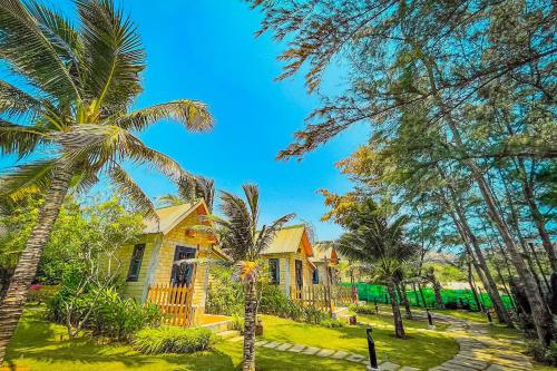a yellow house with palm trees in front of it at Long Hải Channel Beach Resort in Long Hai