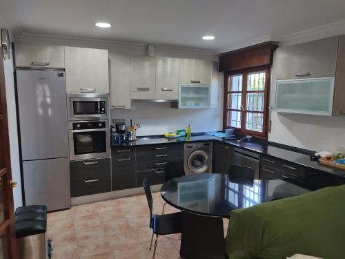 cocina con electrodomésticos de acero inoxidable y mesa en KABIXA ETXEA Casa Rural, Lekeitio, en Guizaburuaga