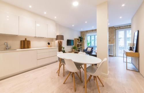 a kitchen and dining room with a white table and chairs at Apartamentos Bellas Artes in San Sebastián