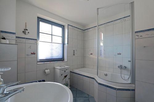 a bathroom with a tub and a shower and a sink at Uns Muschelhus in Zingst