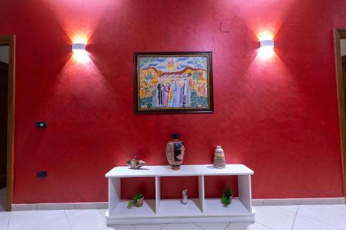 a red wall with a table with a painting on it at Pompei Luxury Rooms in Pompei