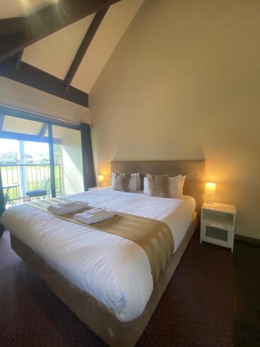 Un dormitorio con una gran cama blanca con ventana. en Hahndorf Motel, en Hahndorf