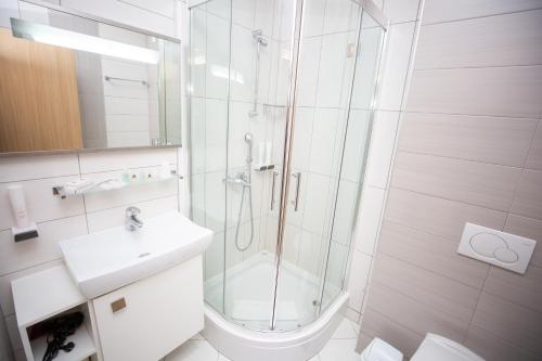 a white bathroom with a shower and a sink at Hotel Herceg in Međugorje