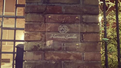 a sign on the side of a brick wall at Hortensia Garden in Macerata