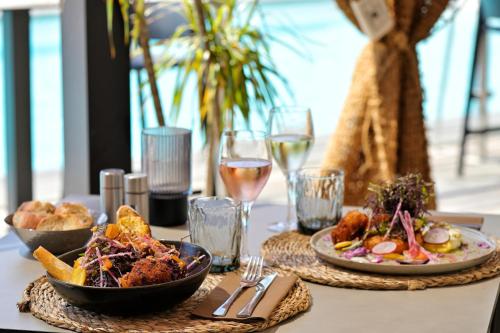 a table with two plates of food and glasses of wine at Hôtel Spa Restaurant La Madrague in Lucciana
