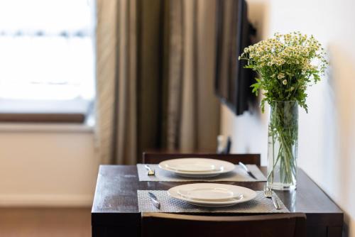 a table with plates and a vase of flowers on it at Starr Hotel Shanghai (Shanghai Railway Station) in Shanghai