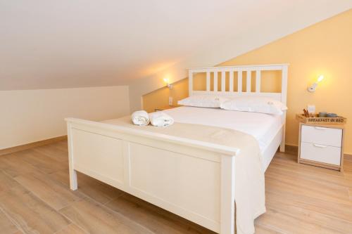 a bedroom with a large white bed with towels on it at Two Olive Trees - Deluxe Apartments in Psathopirgos