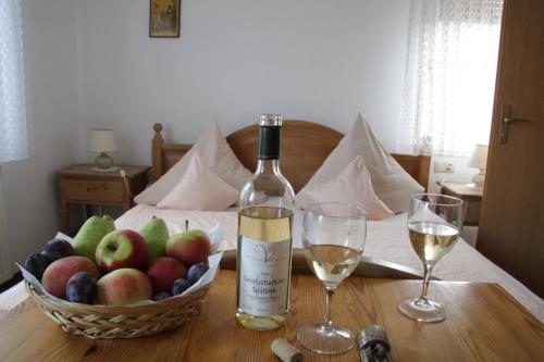 a bottle of wine and a basket of fruit on a table at Weingut und Gästehaus Vongerichten in Oberhausen