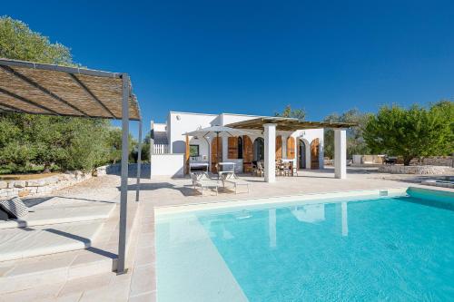 a swimming pool with a gazebo and a house at Cisternino Villa in Olive Groove in Cisternino