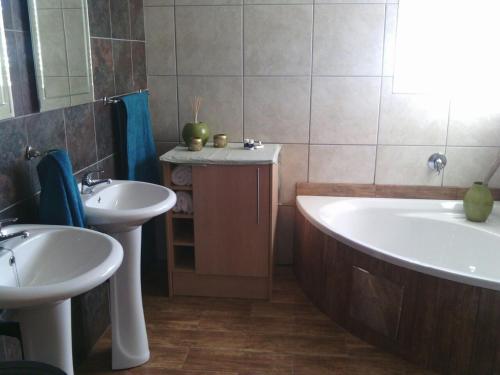 a bathroom with two sinks and a bath tub at Homestay Travel Guest House in Roodepoort