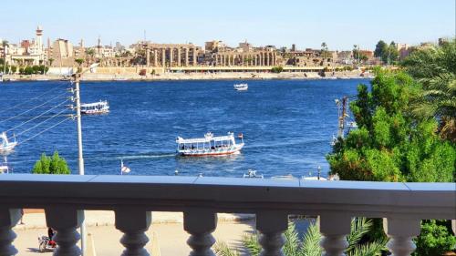 a boat on a river with a city in the background at El Mesala Hotel in Luxor