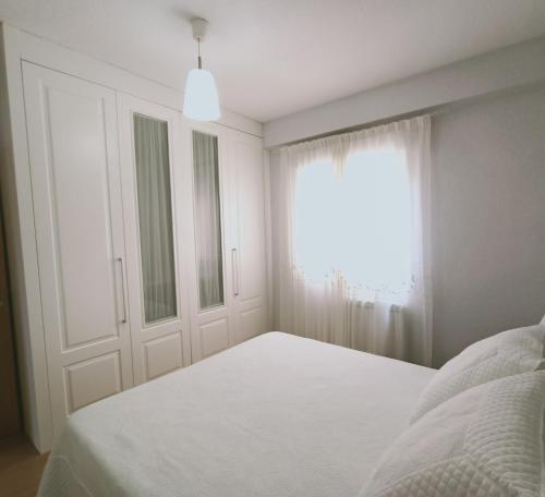 a white bedroom with a bed and a window at Lux Buenavista in Toledo