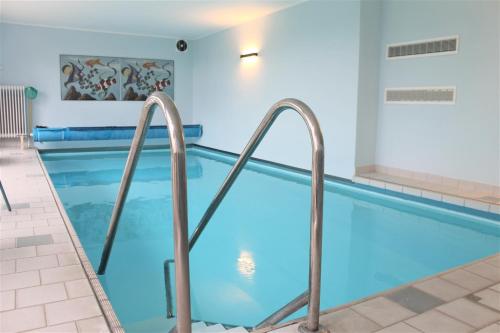 een zwembad met blauw water in een gebouw bij Haus Barbara - Schwimmbad und Sauna im Haus- Whg 7 in Grömitz