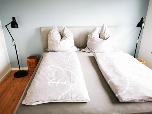 2 Betten mit weißer Bettwäsche und Kissen darauf in der Unterkunft Chalethaus-Chiemsee - 120qm Panorama-Chaletwohnung am Chiemsee - Neubau in Prien am Chiemsee
