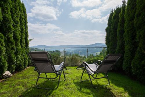 zwei Stühle auf dem Rasen im Garten in der Unterkunft Apartament Na Urlop - Wisła Bukowa Góra - Apartamenty z widokiem na panoramę Wisły in Wisła