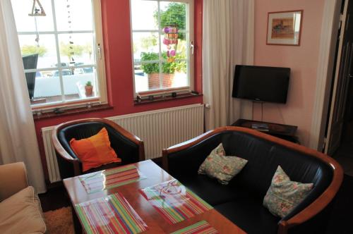 un soggiorno con tavolo, sedie e TV di Fischerhaus am Binnensee a Heiligenhafen