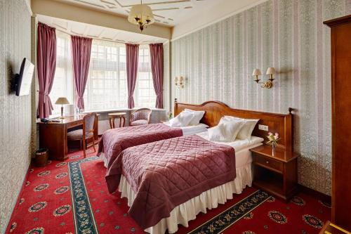 a hotel room with two beds and a desk at Hotel Atlas Deluxe in Lviv
