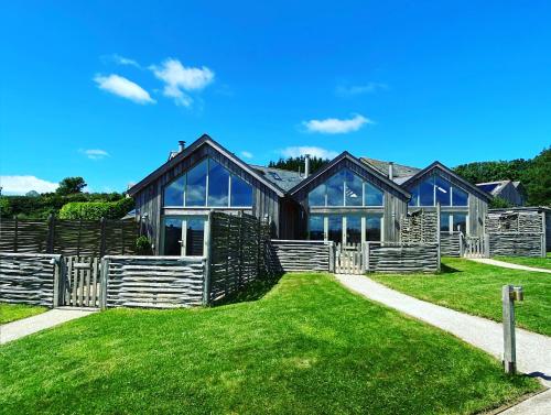 a large wooden house on a green lawn at Merlin Farm Cottages short walk to Mawgan Porth Beach and central location in Cornwall in Mawgan Porth