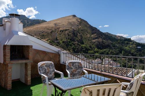 a balcony with a table and chairs and a mountain at La Casa de Esparto in Cazorla