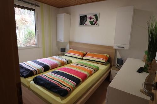 2 Betten mit bunten Kissen auf einem Zimmer in der Unterkunft Haus am See - KEK2 in Tanna